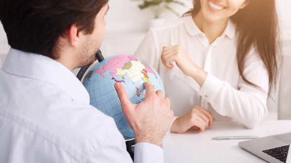 Man choosing country for journey in travel agency