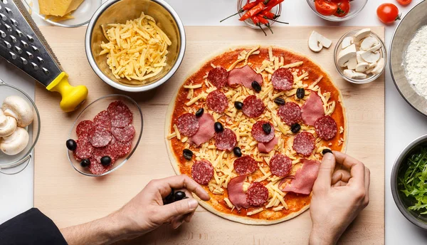 Chef dekoriert italienische Pizza mit schwarzen Oliven — Stockfoto