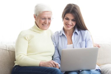 Olgun anne ve Haberler okuma, dizüstü bilgisayar kullanarak kızı