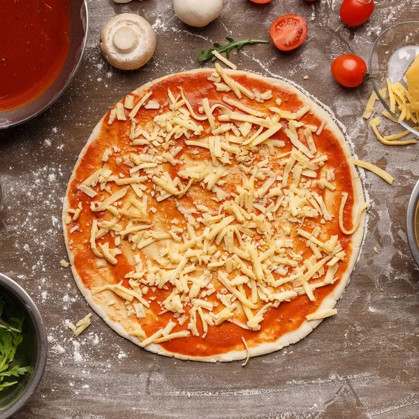 Pizza zubereiten. roher Teig mit geriebenem Käse — Stockfoto