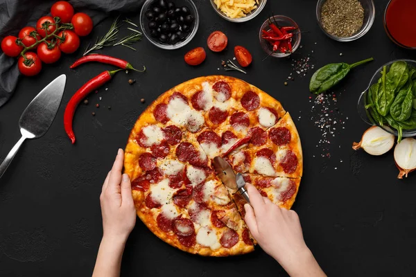 Perempuan memotong pizza pepperoni menjadi irisan, tampilan atas — Stok Foto