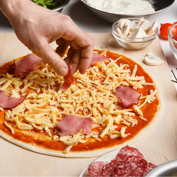 Mann fügt Schinken auf der Pizza hinzu, Nahaufnahme — Stockfoto