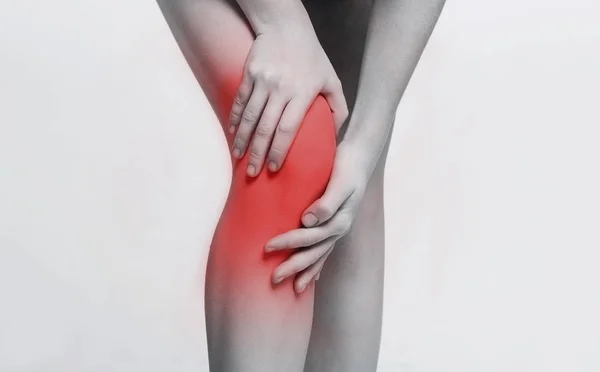 Young woman massaging her painful knee closeup — Stock Photo, Image