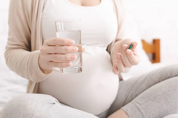 Donna incinta in possesso di pillola e bicchiere d'acqua — Foto Stock