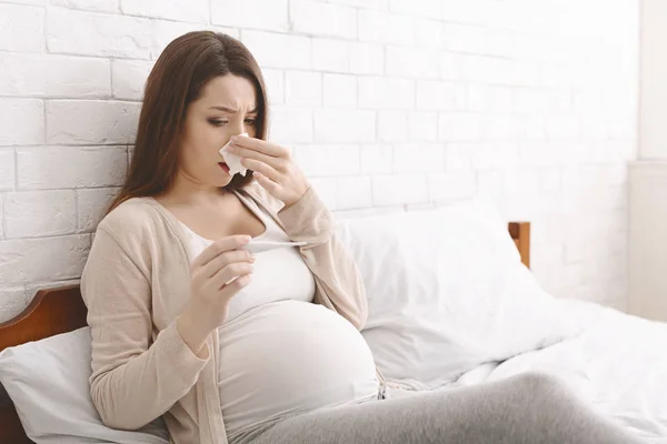 Giovane donna incinta sensazione di malessere con febbre alta, sdraiata sul letto — Foto Stock