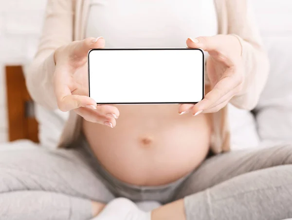 Wanita hamil memegang ponsel dengan layar kosong di dekat perutnya — Stok Foto