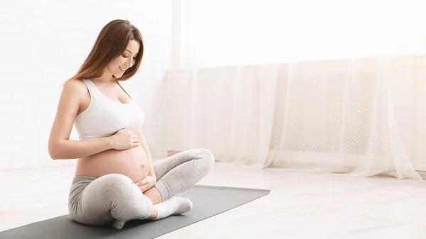 Wanita hamil aktif duduk di lantai setelah melakukan olahraga — Stok Foto