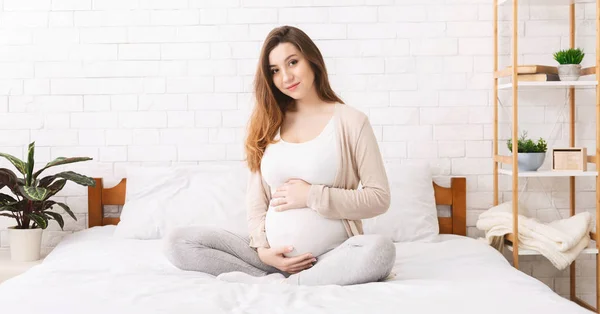 Mulher grávida desfrutando de gravidez em seu quarto — Fotografia de Stock