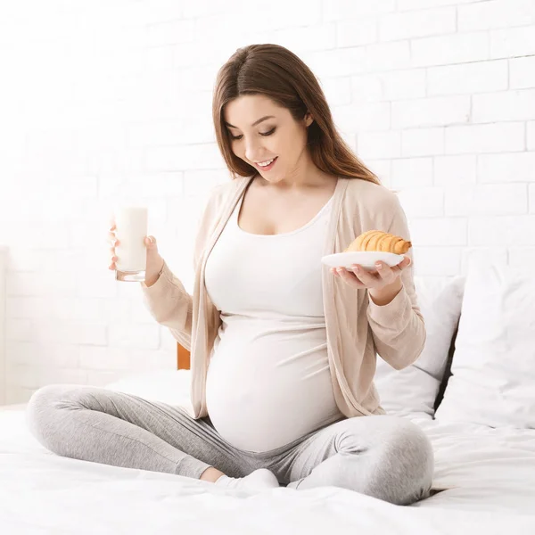 Young pregnant woman having brunch sitting on bed — Stock Photo, Image