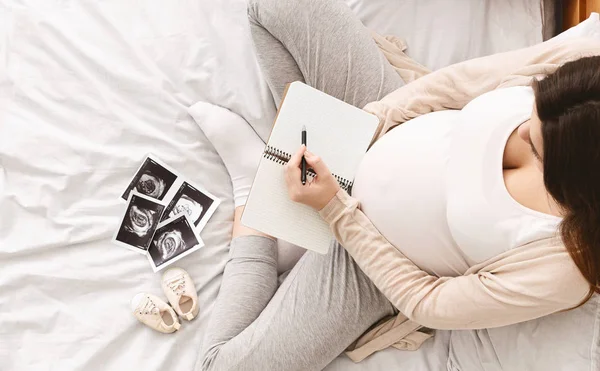 Mujer embarazada haciendo lista de embalaje para el hospital de maternidad — Foto de Stock