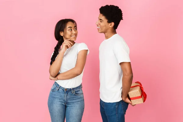 Kille gömmer sig närvarande från hans flickvän, rosa bakgrund — Stockfoto