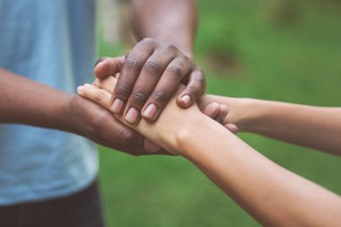 Black caregiver supporting woman hand in park clipart