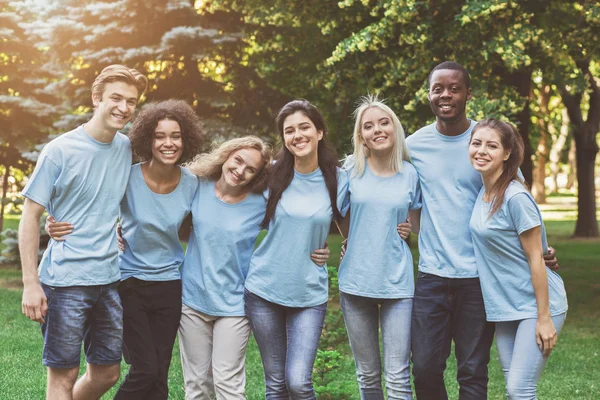 Group of young volunteers embracing at park — Stock Photo, Image