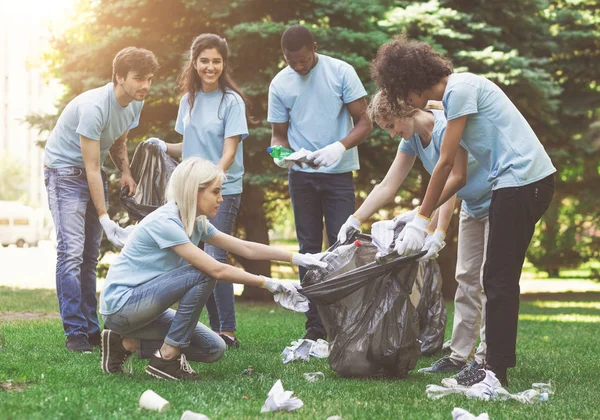 Jóvenes voluntarios recogiendo basura en suumer park — Foto de Stock