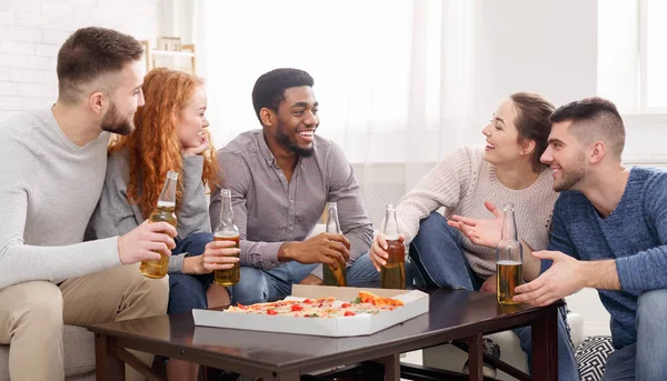 Fiesta en casa. Estudiantes felices comiendo pizza y bebiendo cerveza —  Fotos de Stock