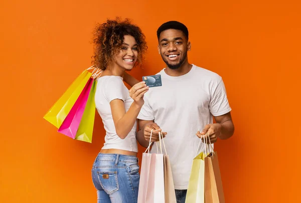 Jonge zwarte paar met boodschappentassen en credit card — Stockfoto