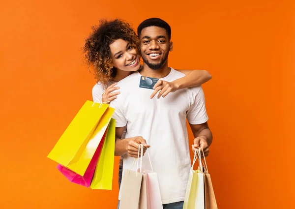 Jovem casal preto com sacos de compras e cartão de crédito — Fotografia de Stock