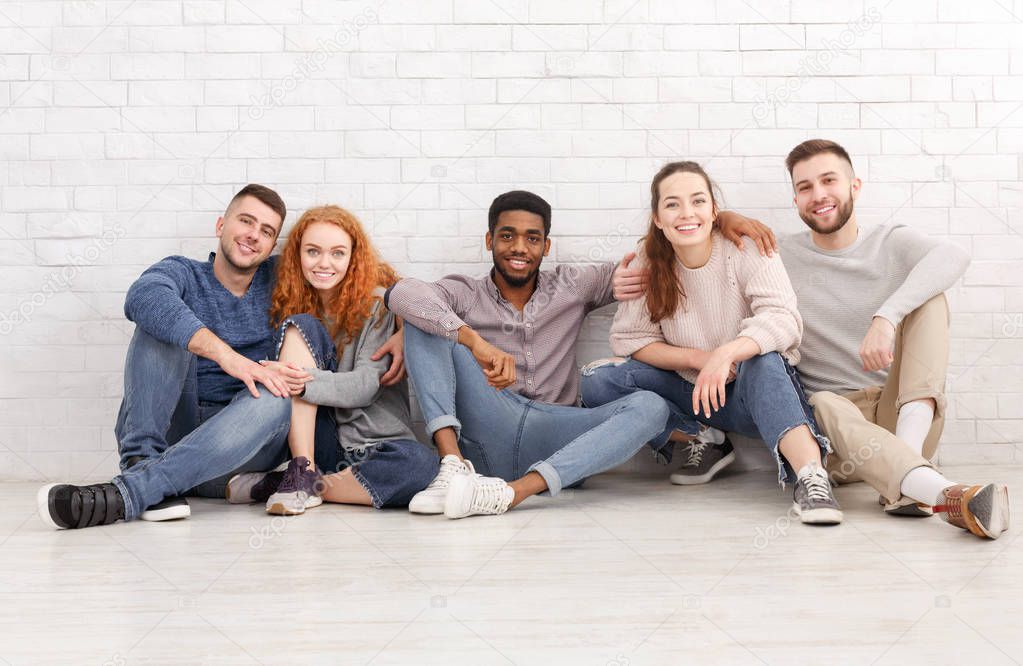 Diverse students sitting on floor and looking at camera