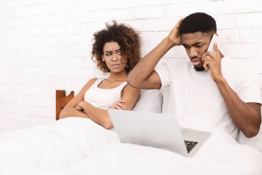 African-american guy working in bed and ignoring his wife clipart