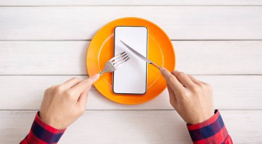 Adam bıçak ve çatal ile boş akıllı telefon yeme
