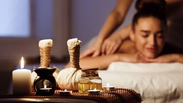 Femme relaxante dans un salon de spa avec des sacs à base de plantes sur un plateau en bois — Photo