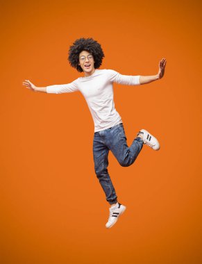 Turuncu studio arka plan üzerinde atlama mutlu zenci