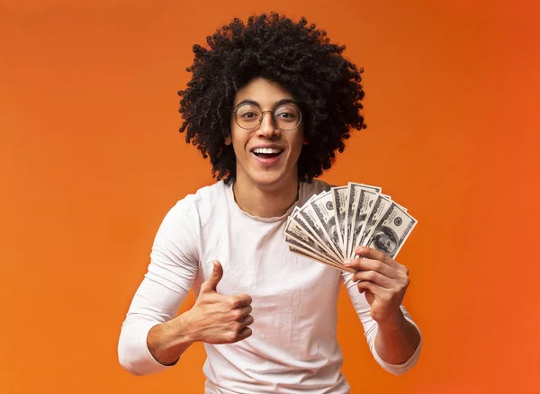 Zwarte man houdt geld op oranje achtergrond — Stockfoto