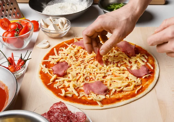 Mann fügt Schinken auf der Pizza hinzu, Nahaufnahme — Stockfoto