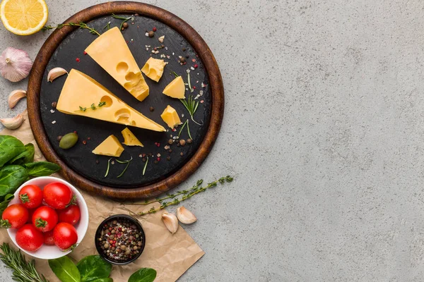 Käse, Tomaten und frische Kräuter auf Betongrund. — Stockfoto