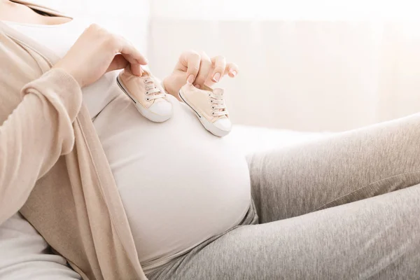 妊娠中の女性の腹に胎児の小さな靴 — ストック写真