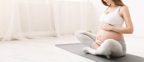 Активная беременная женщина сидит на полу после занятий спортом — стоковое фото