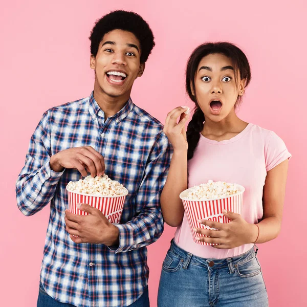 Šokovaný pár jíst popcorn růžové pozadí — Stock fotografie