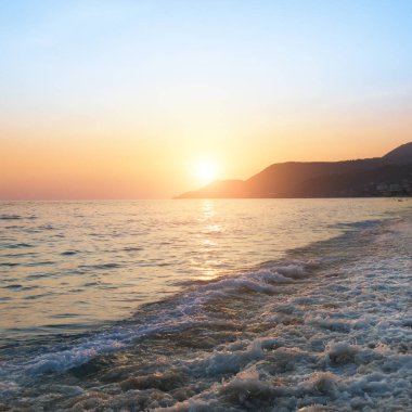 Deniz üzerinde güzel gündoğumu ve açık gökyüzü ile plaj