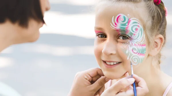 Чарівна маленька дівчинка отримує творчий візерунок на обличчі — стокове фото