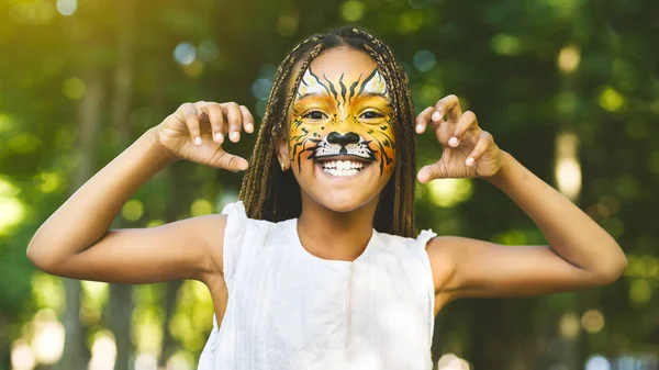 Cheerful little african-american girl with face painting like tiger — Stock Photo, Image