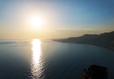 Dağlar ile deniz kıyısında günbatımı