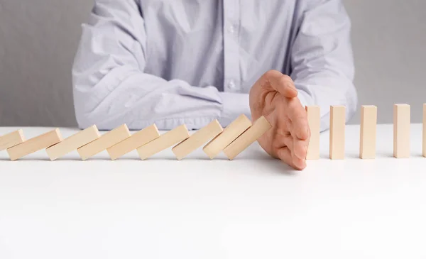 Man stoppen domino effect op witte tafel. — Stockfoto