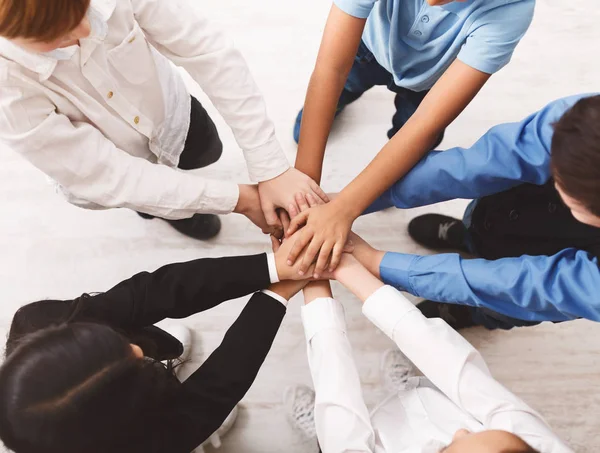 Pupils putting their hands together indoors, top view — Stock Photo, Image