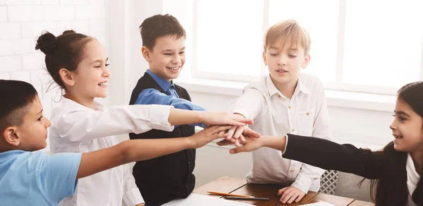 Niños poniendo sus manos juntas en el aula —  Fotos de Stock