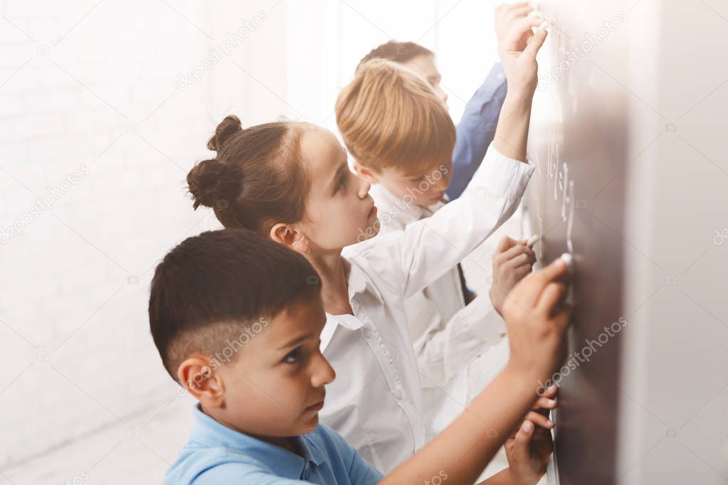 Children writing maths equations on the board
