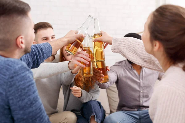 Jeunes amis cliquetis bouteilles de bière, ayant fête à la maison — Photo