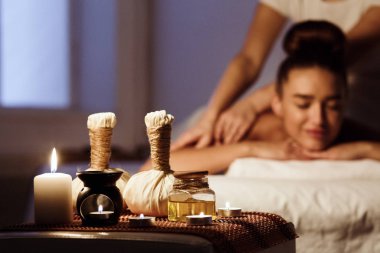 Ahşap tepsi üzerinde bitkisel çantalar ile Spa salonunda rahatlatıcı kadın