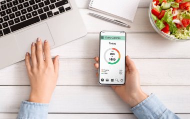 Akıllı telefon kullanarak kadın elleri ve taze salata yeme