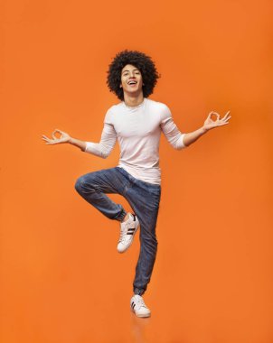 Tek ayak üstünde Dengeleme orta havada oturan komik genç adam