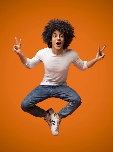 Радостный афро-американец, прыгающий в воздух, демонстрирующий V-знаки — стоковое фото