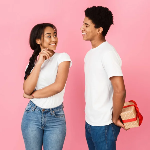 Tipo ocultando regalo de su novia, fondo rosa — Foto de Stock