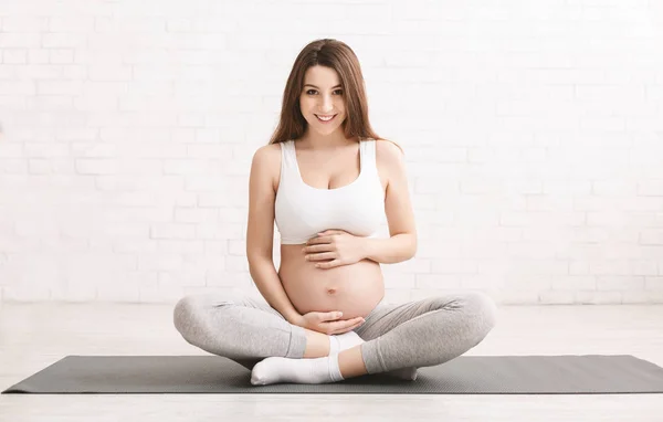 Wanita hamil aktif duduk di lantai setelah melakukan olahraga — Stok Foto