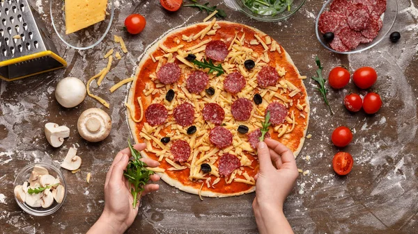 Gotowania pizza. Szef kuchni dodając rukola do pizzy — Zdjęcie stockowe