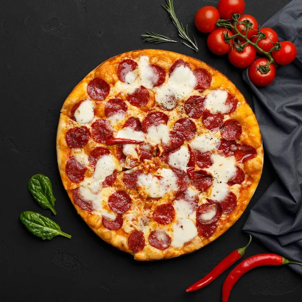 Pizza de pepperoni e ingredientes de cocina sobre fondo negro — Foto de Stock