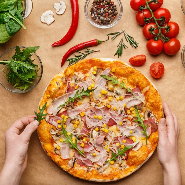 Frau dekoriert hausgemachte Pizza und fügt Rucola hinzu — Stockfoto